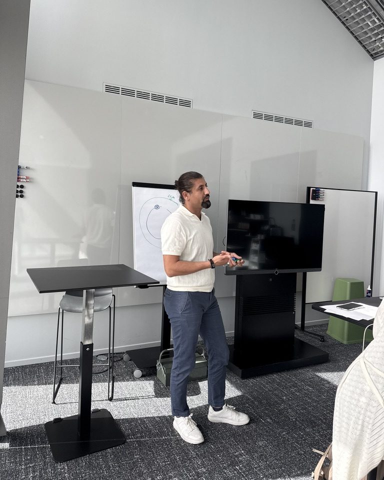 Hüseyin Torun bei einem Vortrag vor Flipchart und Bildschirm